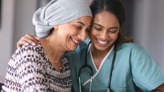 Healthcare worker embracing patient with head wrap Healthcare worker embracing patient with head wrap