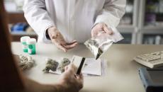 Person in lab coat showing person bags of cannabis Person in lab coat showing person bags of cannabis