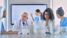 Healthcare workers meeting with large screen in background Healthcare workers meeting with large screen in background
