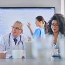 Healthcare workers meeting with large screen in background Healthcare workers meeting with large screen in background