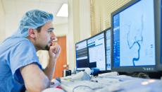 Healthcare worker in scrubs looking at medical image on screen Healthcare worker in scrubs looking at medical image on screen