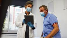 Doctor in mask showing tablet to patient in mask Doctor in mask showing tablet to patient in mask