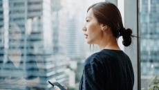 A person holding a smartphone looking out the window A person holding a smartphone looking out the window