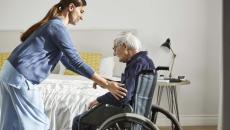 Healthcare worker assisting patient in wheelchair Healthcare worker assisting patient in wheelchair