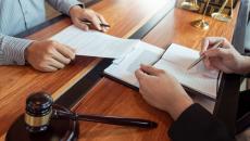 Two people reviewing documents with a gavel nearby Two people reviewing documents with a gavel nearby