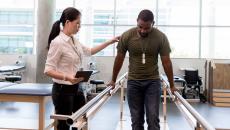 Physical therapist helping patient walk Physical therapist helping patient walk