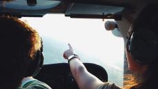 In a plane, a copilot points to a destination on the horizon. In a plane, a copilot points to a destination on the horizon.