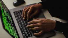 Hands typing on a laptop showing code only Hands typing on a laptop showing code only