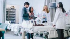 group of healthcare workers talking over hospital bed group of healthcare workers talking over hospital bed