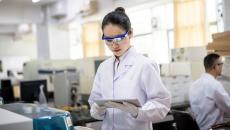 A female healthcare researcher in a lab looks at a tablet. A female healthcare researcher in a lab looks at a tablet.