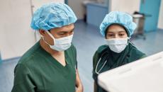Two surgeons checking on an operation's progress through a digital monitor Two surgeons checking on an operation's progress through a digital monitor