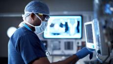 A surgeon checking a monitor in the operating room A surgeon checking a monitor in the operating room