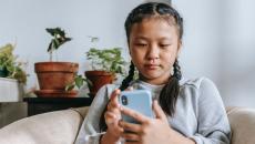 Young person sits on a couch and types on a mobile phone Young person sits on a couch and types on a mobile phone